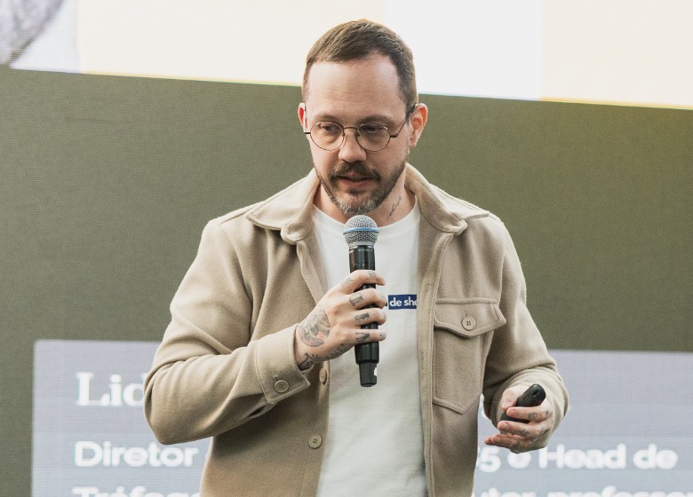 Andre Raittz falando em uma palestra, de microfone na mão